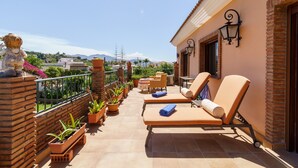 Un balcón con dos sillones de descanso, plantas en macetas y vista al paisaje.