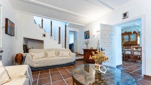 Un salon comprenant un canapé, une table basse en verre et un coin repas avec des chaises et un buffet.