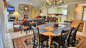 A dining area with a large wooden table, multiple chairs, a chandelier, and a stone fireplace. - Stunning 3BR chalet in Seven Devils, NC, featuring mountain views and a hot tub. (Seven Devils)