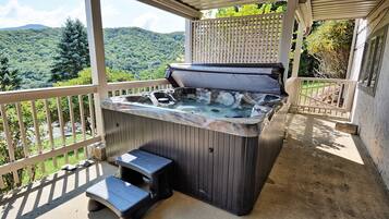 Un bain à remous avec des marches, un patio couvert et une vue sur un paysage montagneux.