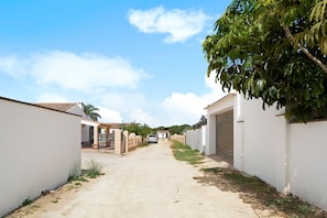 Une rue résidentielle bordée de maisons, avec une voiture et un ciel dégagé.