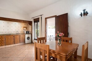 Une cuisine avec des meubles de rangement en bois, un lave-linge et une table à manger avec des chaises.