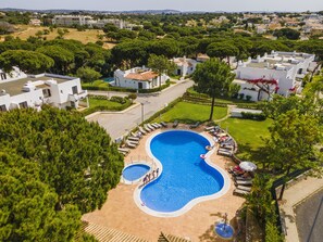A large swimming pool surrounded by lounge chairs and umbrellas, with a view of a residential area in the background. - Albufeira Family Holidays at Balaia 143 (Albufeira)