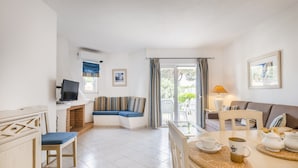 A cozy living room with a sofa, a dining table with chairs, a fireplace, and a TV. - Albufeira Family Holidays at Balaia 143 (Albufeira)