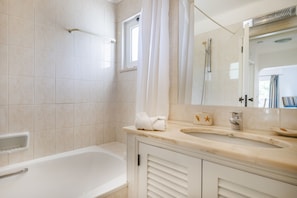 A bathroom with a bathtub, a shower, a vanity with a sink, and a mirror. - Albufeira Family Holidays at Balaia 143 (Albufeira)