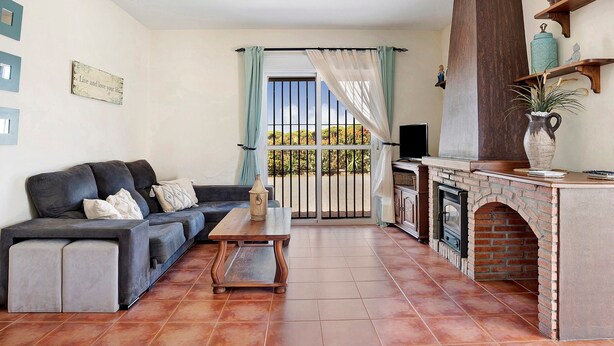 Una sala de estar con sofá, mesa de centro, chimenea y vistas a través de una puerta.
