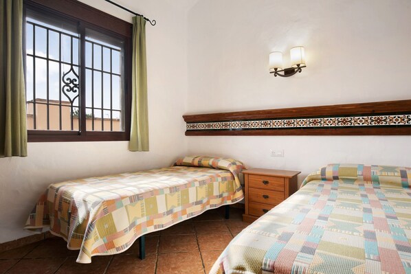 A room with two beds, a window with curtains, a nightstand, and a wall-mounted light fixture. - Villa Perez Zara 3 with Pool, Open Terrace & Wi-Fi (Conil)