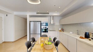 Una cucina moderna con isola centrale, elettrodomestici in acciaio inossidabile e un'area pranzo con sedie e tavolo apparecchiato per due.