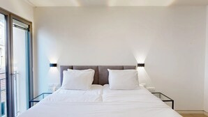 Una moderna camera d'albergo con un letto grande, due comodini e un tavolino da notte.