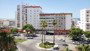 A multi-story building with a central courtyard, palm trees, and a clear sky. - Apartment 'Quarteira Beach Iii' with Balcony, Wi-Fi and Air Conditioning (Quarteira)