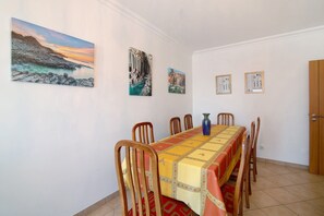 Un espace repas comprenant une longue table, des chaises et des œuvres d’art murales.