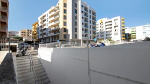 A multi-story residential building with balconies, a staircase, and a parked scooter. - Apartment 'Quarteira Beach I' with Balcony, Wi-Fi and Air Conditioning (Quarteira)