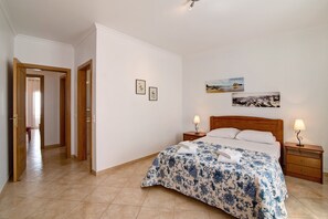 Une chambre à coucher avec un lit, des tables de chevet, une tête de lit en bois et des œuvres d’art murales.