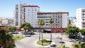 A multi-story building with a central courtyard, palm trees, and a clear sky. - Apartment 'Quarteira Beach Ii' with Balcony, Wi-Fi and Air Conditioning (Quarteira)