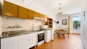 Una cocina con armarios blancos, estufa, microondas y un comedor con mesa y sillas.