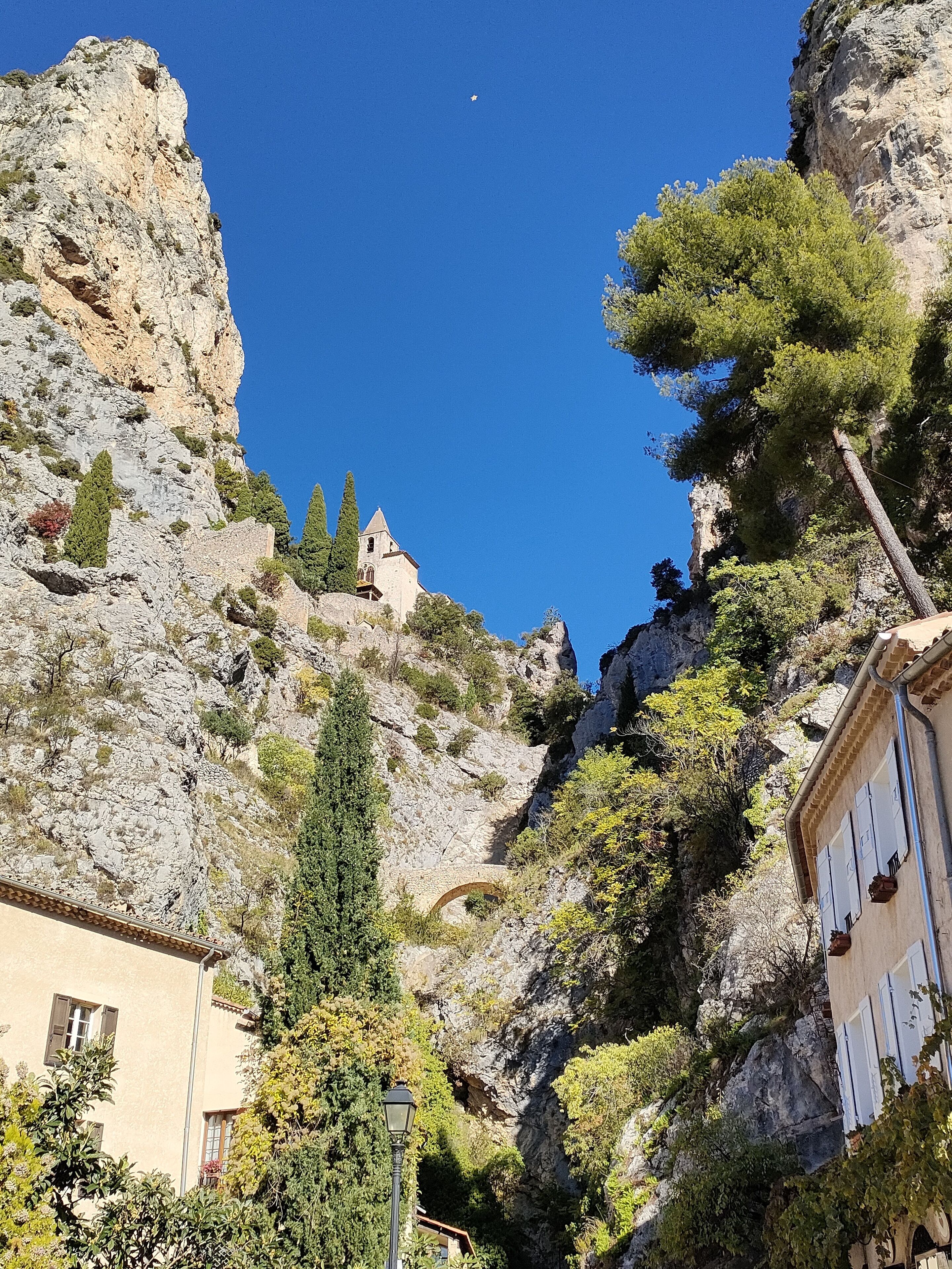 Un paysage montagneux avec un bâtiment doté d’une arche en pierre et d’un clocher.