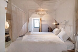 Une chambre à coucher avec un grand lit, une table de chevet, une fenêtre et un baldaquin.