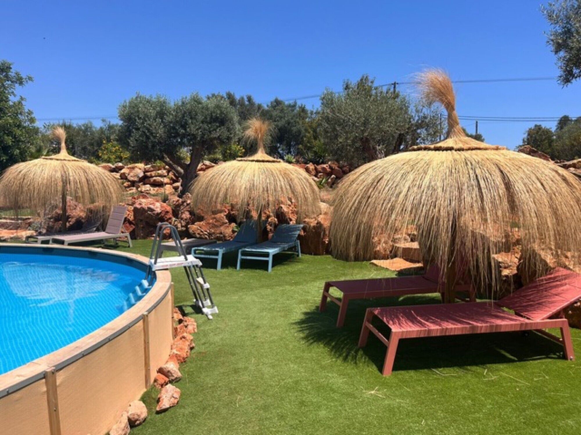A swimming pool with lounge chairs and thatched umbrellas.
