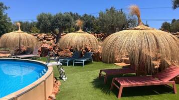 A swimming pool with lounge chairs and thatched umbrellas.