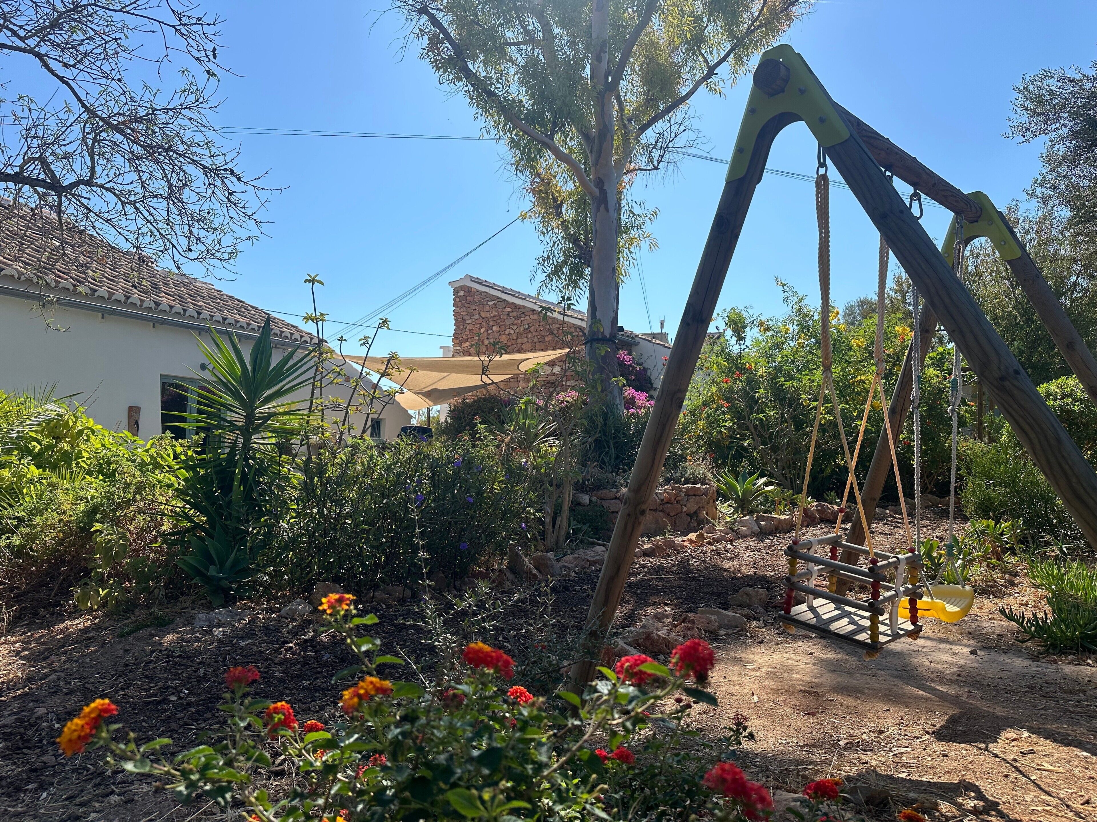 Un giardino con un’altalena, un muro in pietra e un edificio con tetto in tegole.