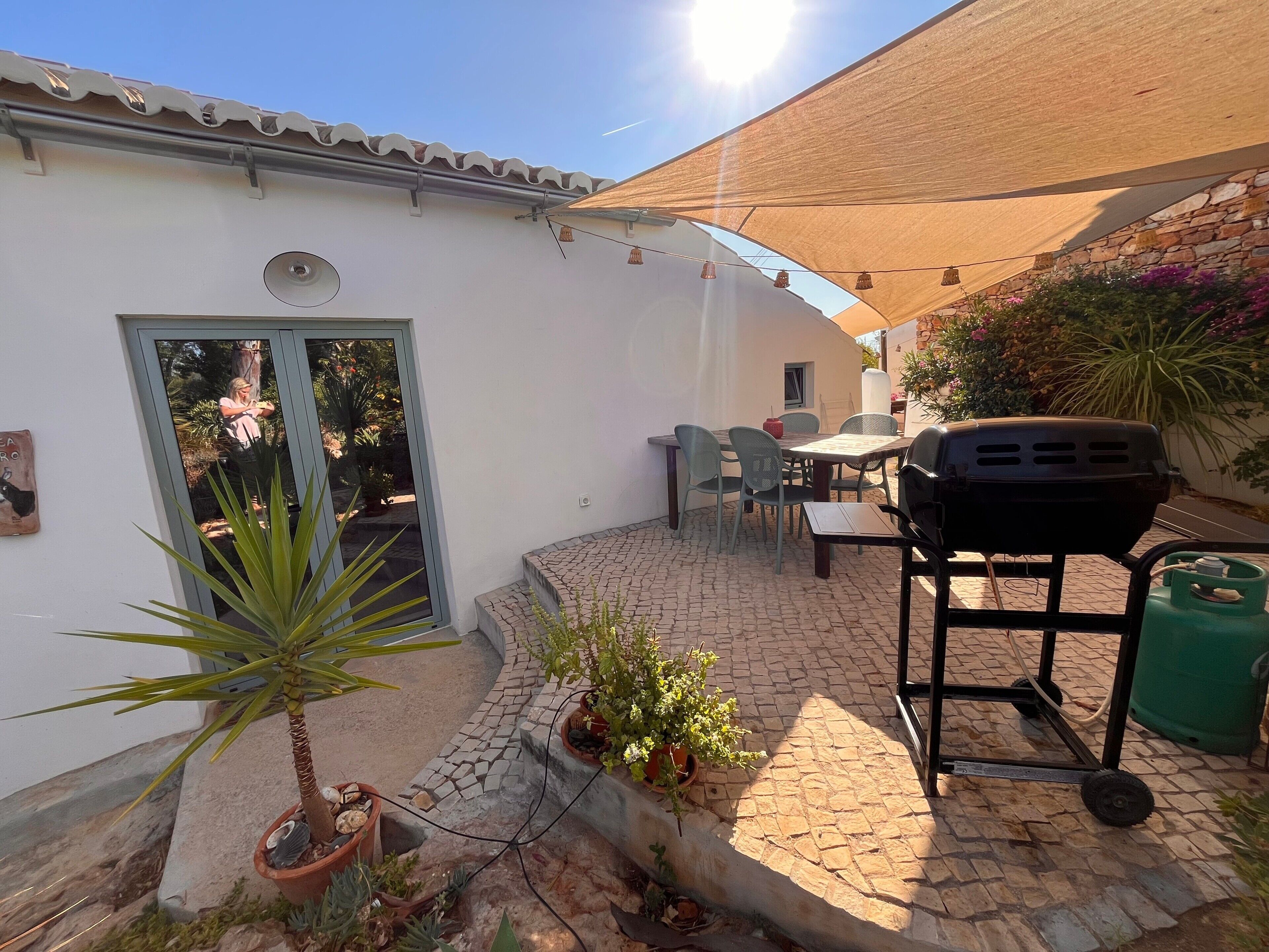 A patio with a grill, outdoor seating, and potted plants.
