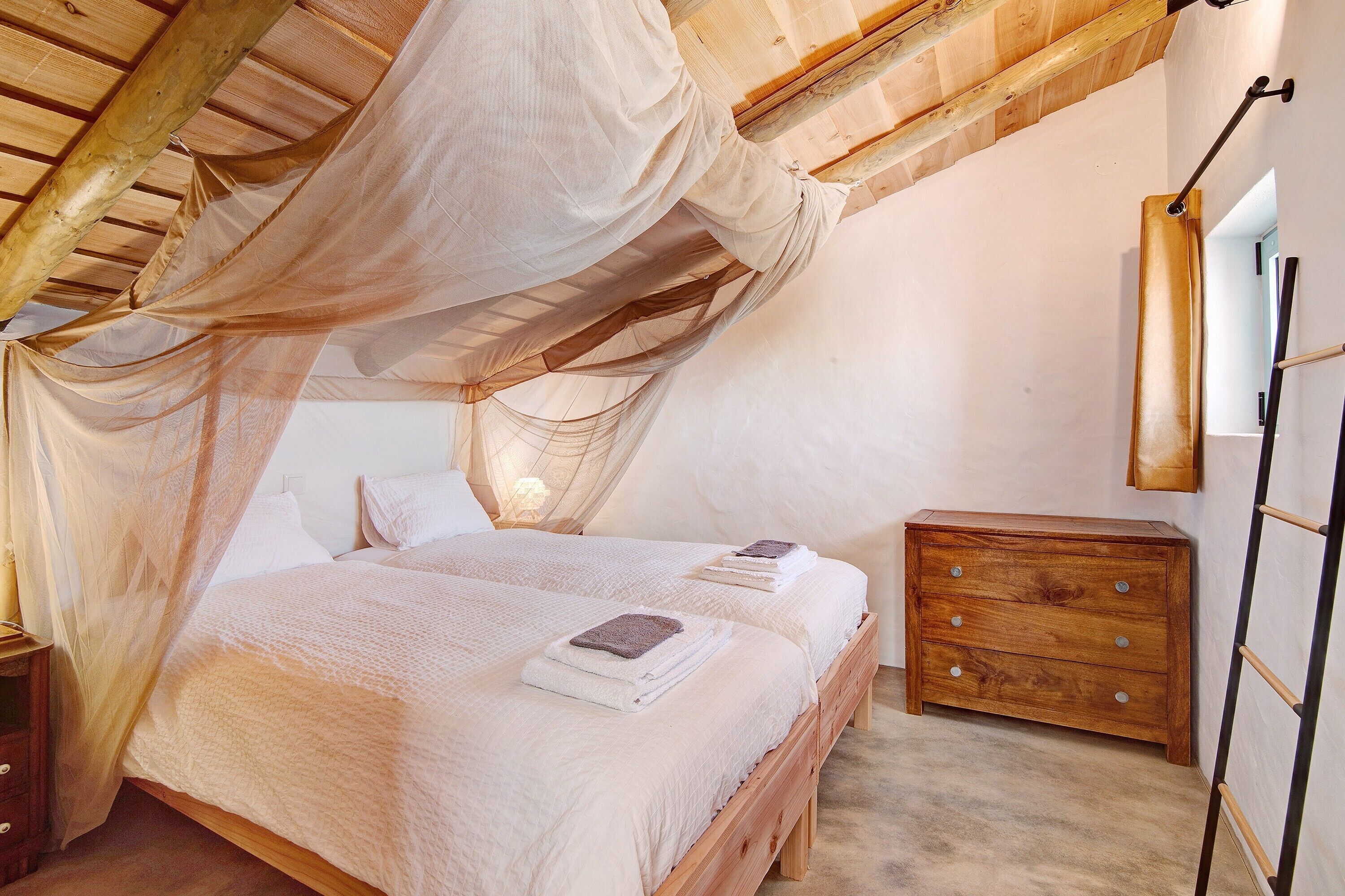 Een slaapkamer met een hemelbed, houten hoofdbord, nachtkastjes en een kledingkast.