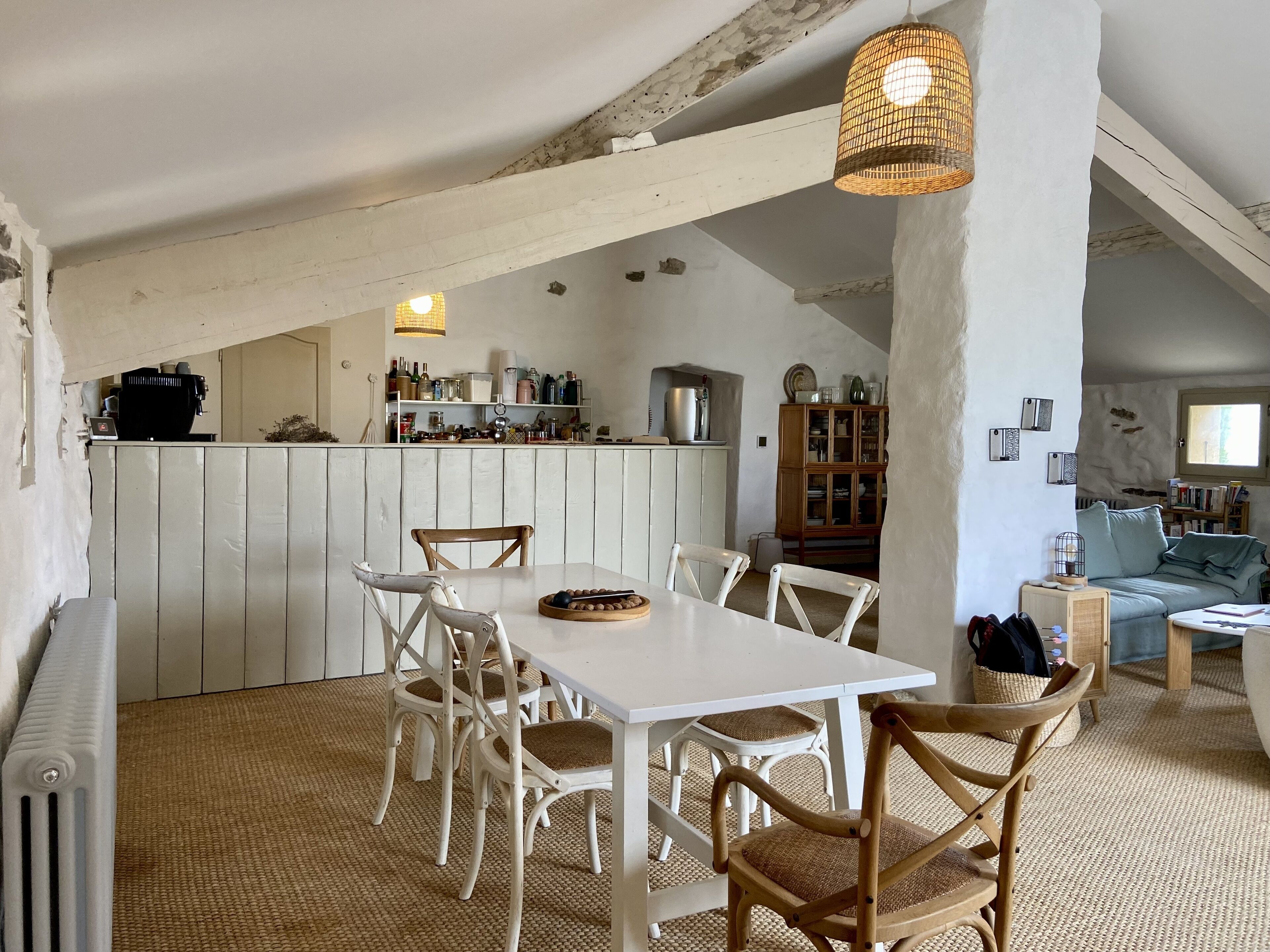 Une cuisine rustique avec des meubles de rangement en bois, une table à manger avec des chaises et un luminaire suspendu.
