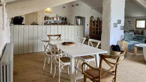 Una cocina rústica con armarios de madera, una mesa de comedor con sillas y una lámpara colgante.