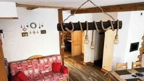 Ein gemütliches Zimmer mit einer gemusterten Couch, einem Holzesstisch und einer Pendelleuchte.