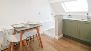 A modern kitchen with a skylight, white walls, and wooden flooring. - The Hayloft (Matlock)