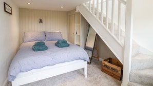 A bedroom with a bed, a wooden ladder, and a crate labeled 'MUDDY BOOTS'. - The Hayloft (Matlock)