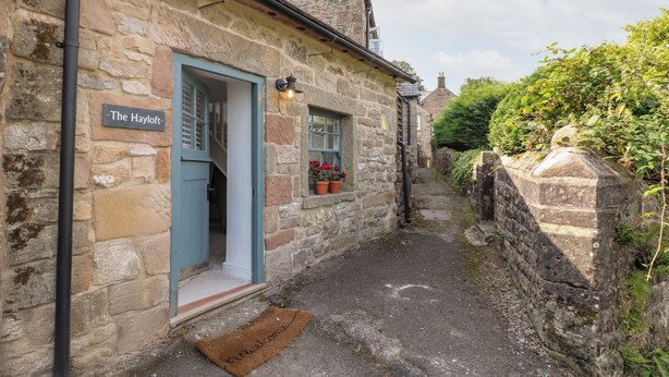 A stone building with a blue door labeled "The Hayloft." - The Hayloft (Matlock)
