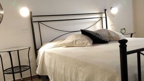 A bedroom with a bed, a small table, and a wall clock. - Cozy apartment in the center 2km from the sea (Bosa)
