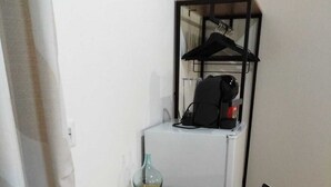 A small room with a wooden table, a black chair, a glass vase, and a clothing rack with a black bag. - Cozy apartment in the center 2km from the sea (Bosa)