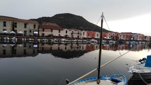 A harbor with boats docked, a building with a red roof, and a mountain in the background. - Cozy apartment in the center 2km from the sea (Bosa)