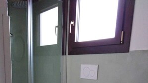 A bathroom with a toilet, a small wooden stool, a sink, and a glass-enclosed shower. - Cozy apartment in the center 2km from the sea (Bosa)