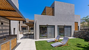 A modern house with a patio, a bar area, and two lounge chairs. - Paligremnos Residence I, sublime beachside retreat (Plakias)