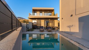 A modern two-story house with a swimming pool, outdoor seating, and a view of the hills. - Paligremnos Residence I, sublime beachside retreat (Plakias)