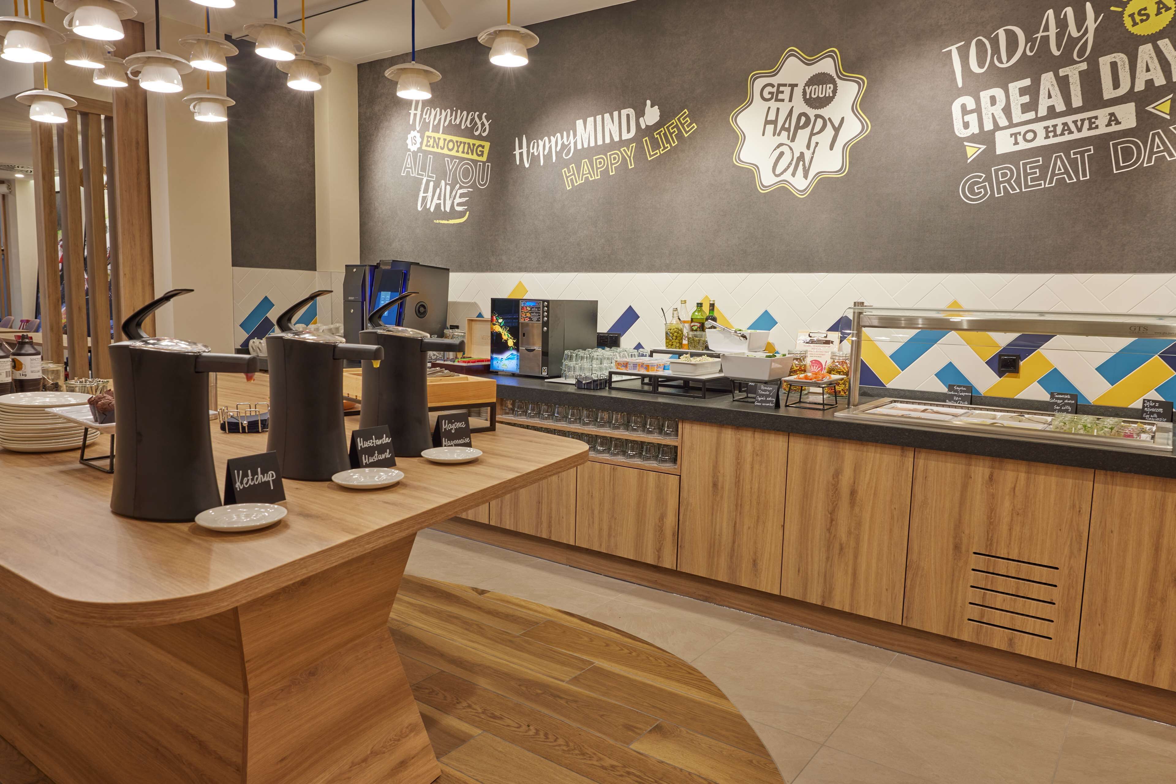 Un café moderne avec un comptoir en bois, des distributeurs de condiments et un mur orné de citations inspirantes.