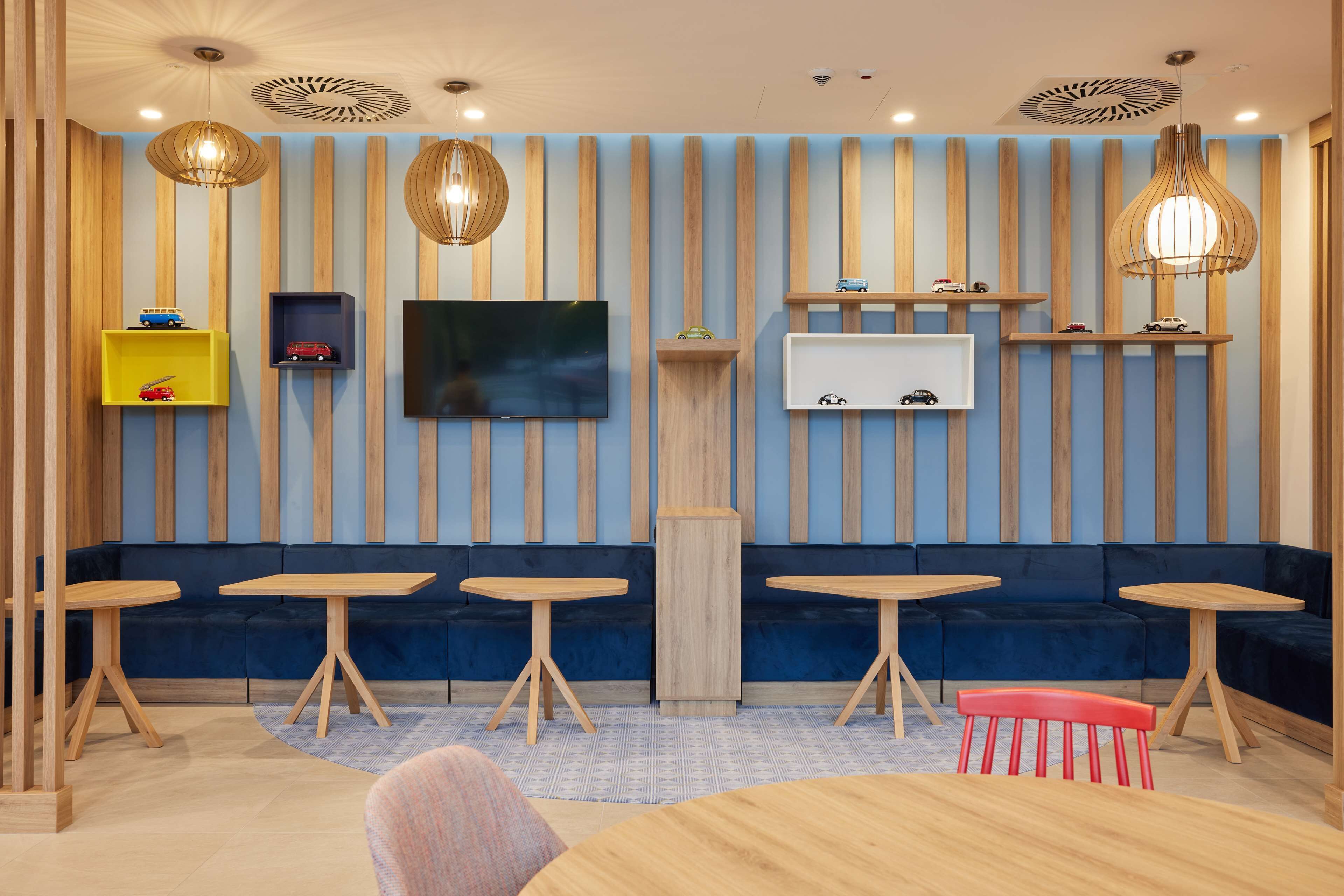 Un interior moderno con una paleta de colores azul y madera, que incluye un sofá, mesas y estanterías decorativas.