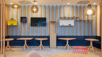 Ein modernes Interieur mit blau-holzfarbenem Farbkonzept, das eine Couch, Tische und dekorative Regale zeigt.