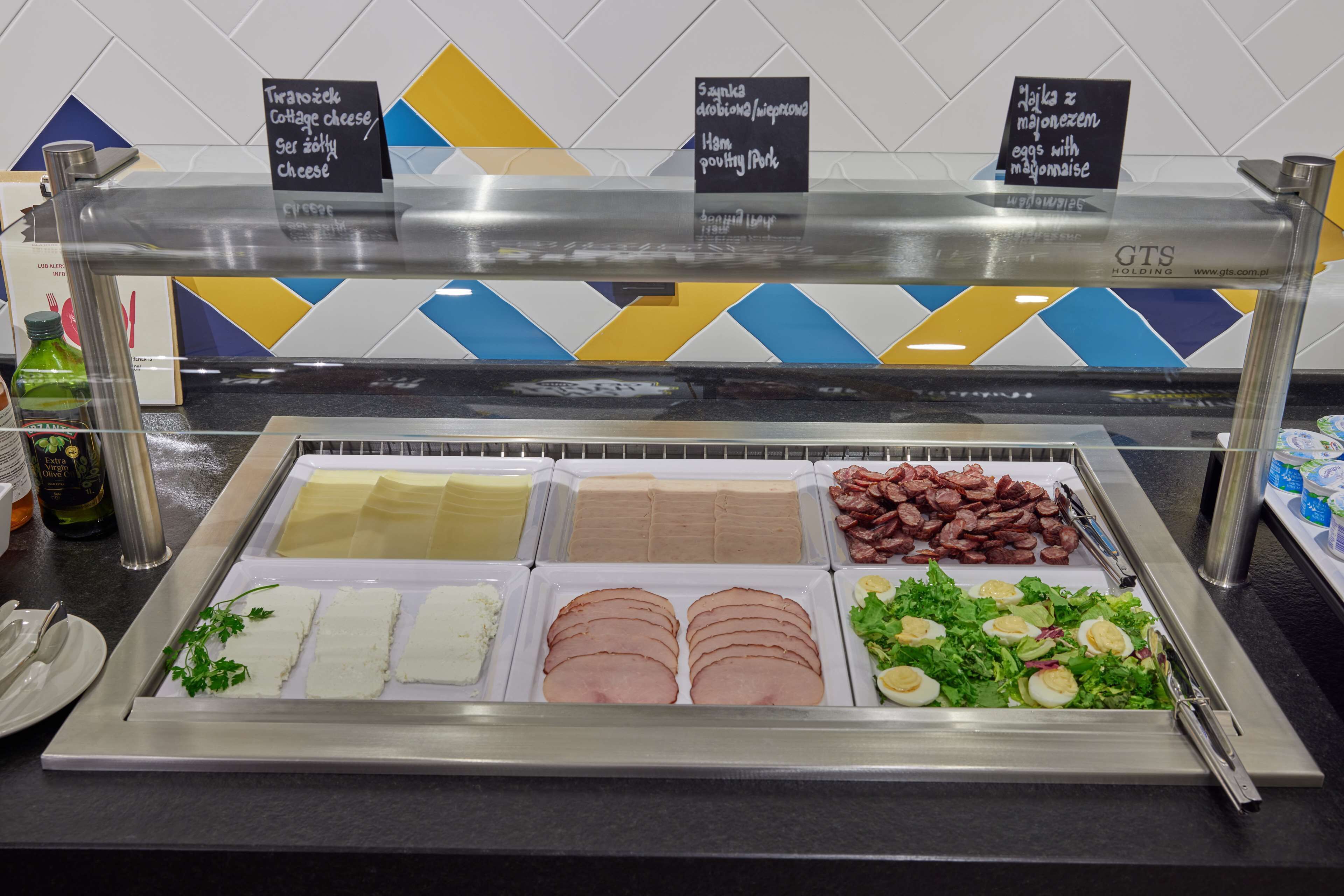 Un bufé con diversas opciones de comida, incluyendo queso, jamón y ensaladas.