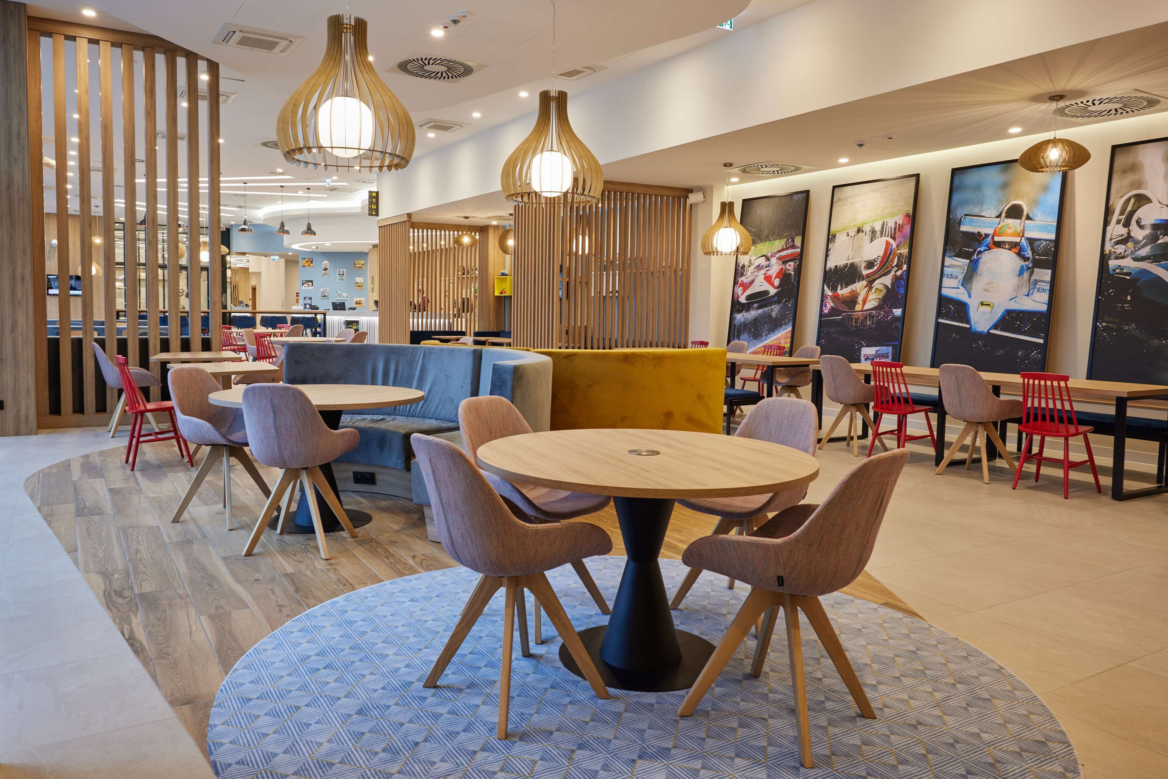 Un intérieur de restaurant moderne avec des tables rondes, des sièges rembourrés et des luminaires suspendus.