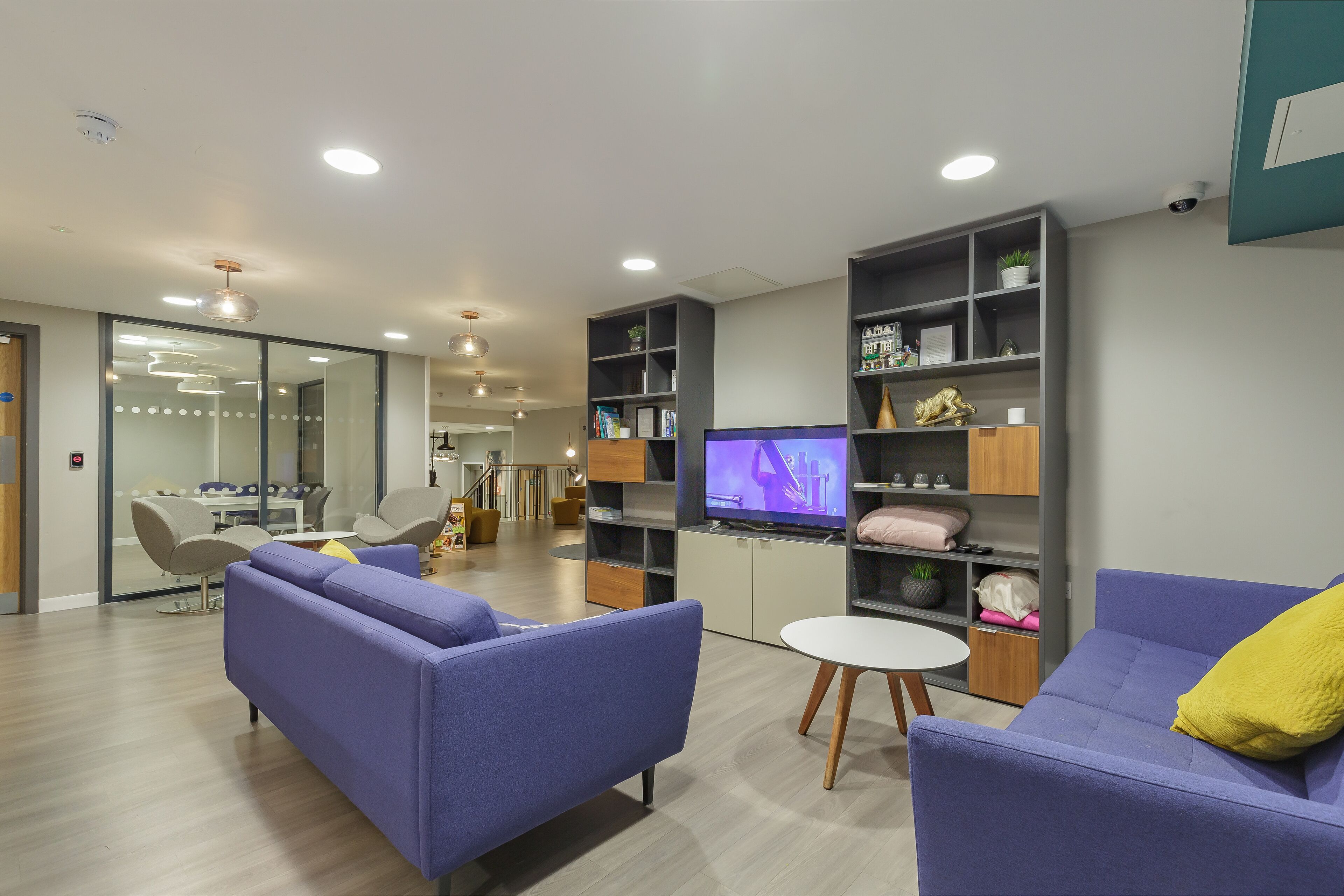 A modern living room with two sofas, a TV, and built-in shelving.