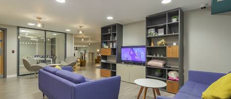 A modern living room with two sofas, a TV, and built-in shelving.