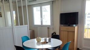 Ein Essbereich mit einem runden Tisch, vier Stühlen, einem Fernseher und einem Schrank.