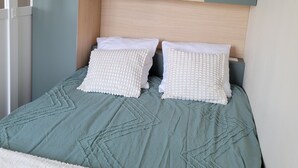 Ein Schlafzimmer mit einem Bett, zwei Kissen, einem Holz-Kopfteil und einer eingebauten Ablagefläche.