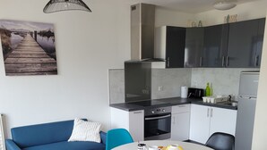 Eine moderne Küche mit Essbereich, ausgestattet mit einem blauen Sofa, einem runden Tisch mit Stühlen und einer Pendelleuchte.