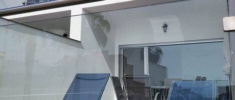 A modern two-story building with a glass balcony, outdoor seating area, and a clear view of the surrounding area.