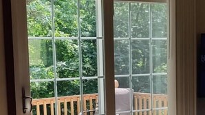A room with a sliding glass door leading to an outdoor patio with a wooden deck and seating area. - Secluded Cabin Retreat – Peace, Privacy & Nature (Mansfield)